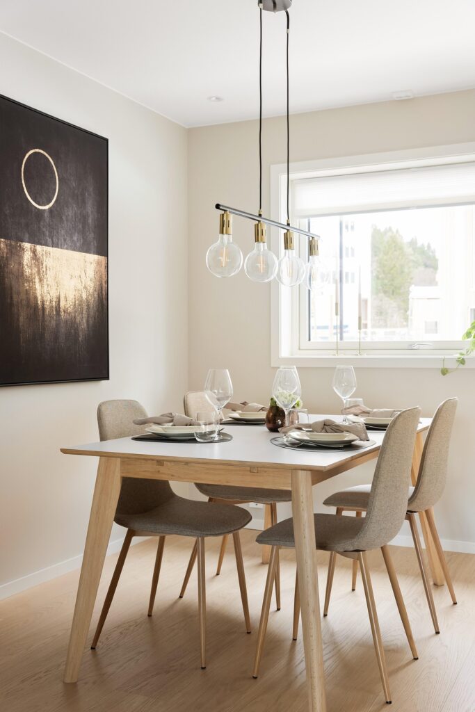 Dining area in a light room and and brown and gold abstract painting