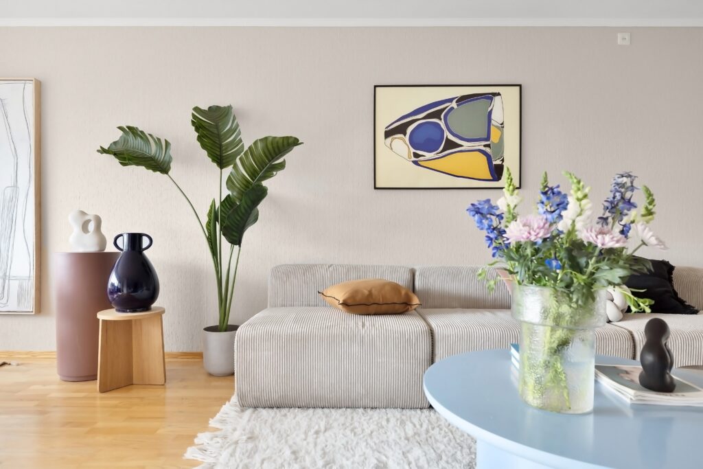 a living room area with a white sofa, plants and framed art in yellow snd light purple