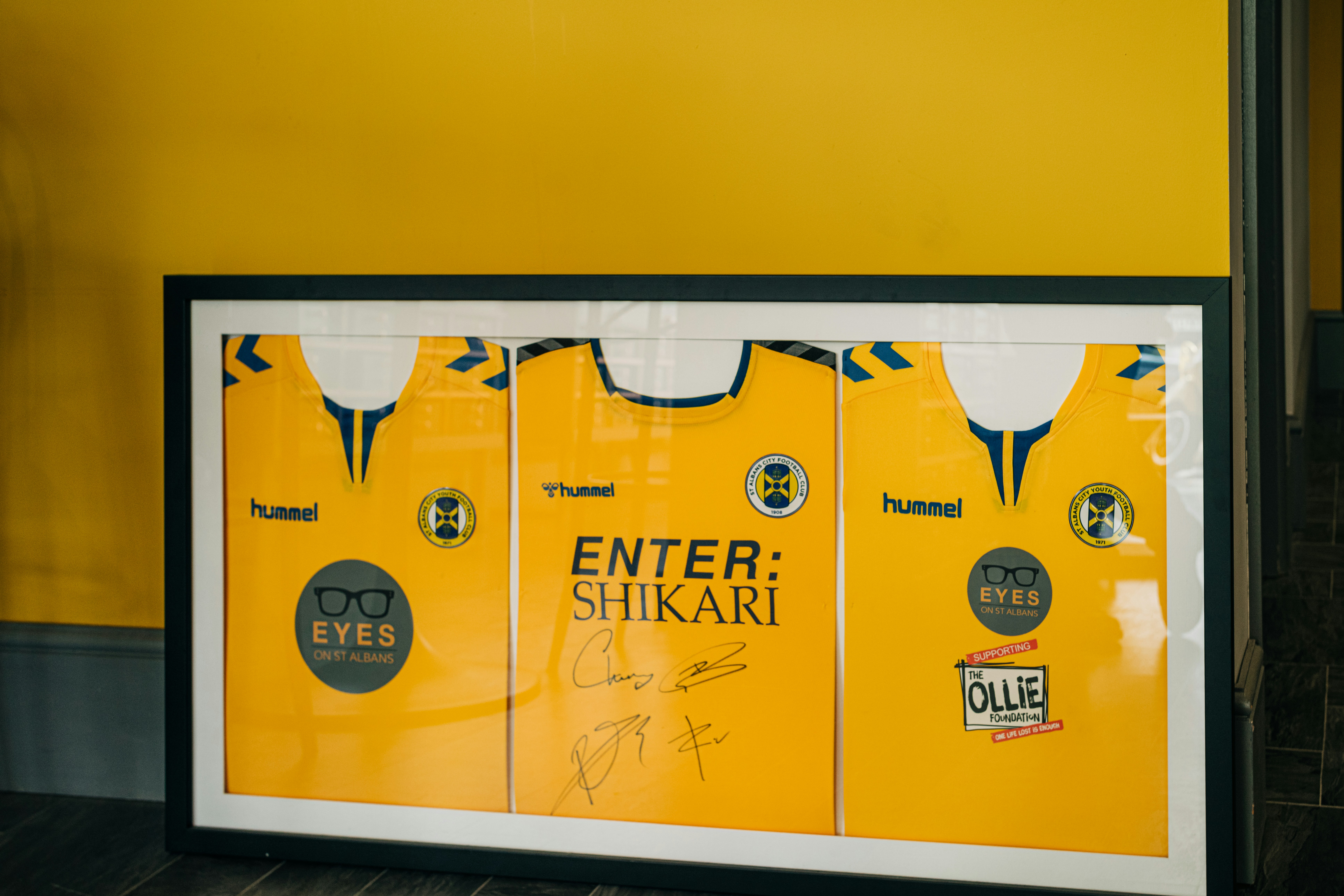 a trio of yellow t shirts framed in a 3D frame